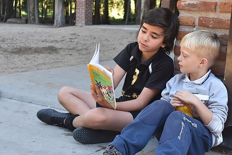 Alumno de 6to de primaria leyendo a uno de 1ro