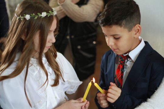 Un alumno y una alumna tomando la 1ra comunión